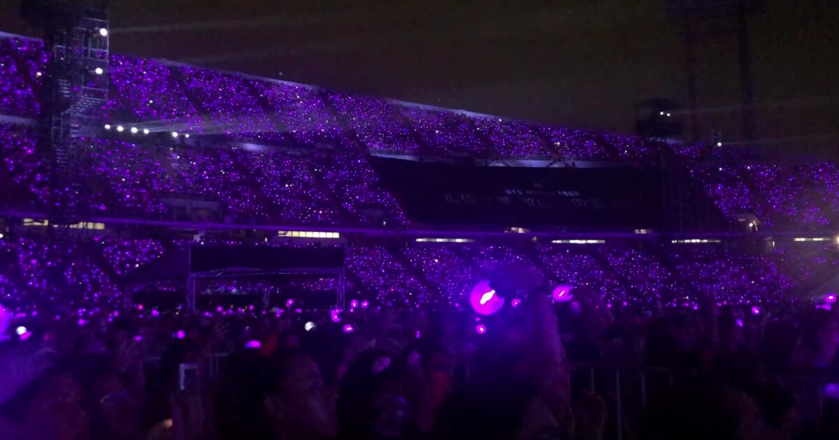 Mar de lightsticks morados del fandom ARMY durante un concierto K-pop en estadio