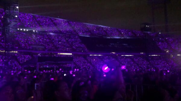 Mar de lightsticks morados del fandom ARMY durante un concierto K-pop en estadio