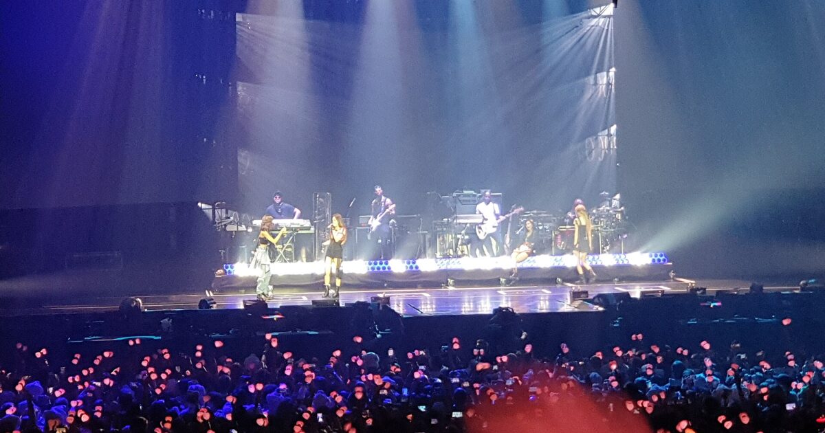 Escenario K-pop con audiencia y lightsticks rosas durante un concierto