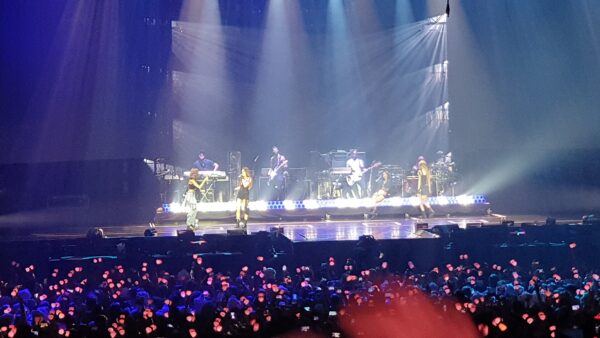 Escenario K-pop con audiencia y lightsticks rosas durante un concierto