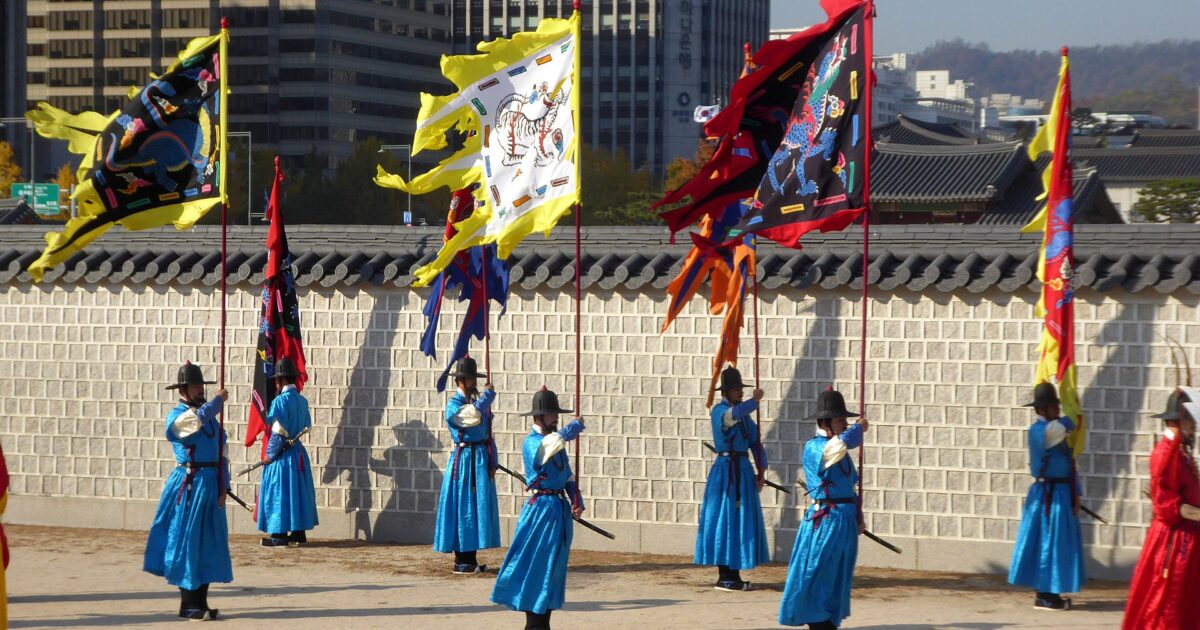 Guardias del palacio Gyeongbokgung en Seúl con hanbok y banderas durante la ceremonia tradicional de cambio de guardia