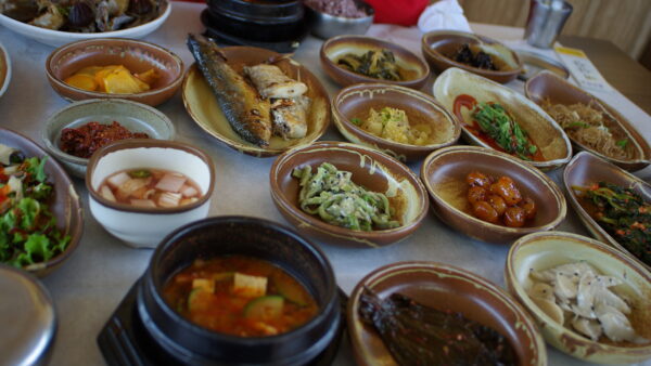 Mesa repleta de banchan y platos coreanos, como en un mukbang